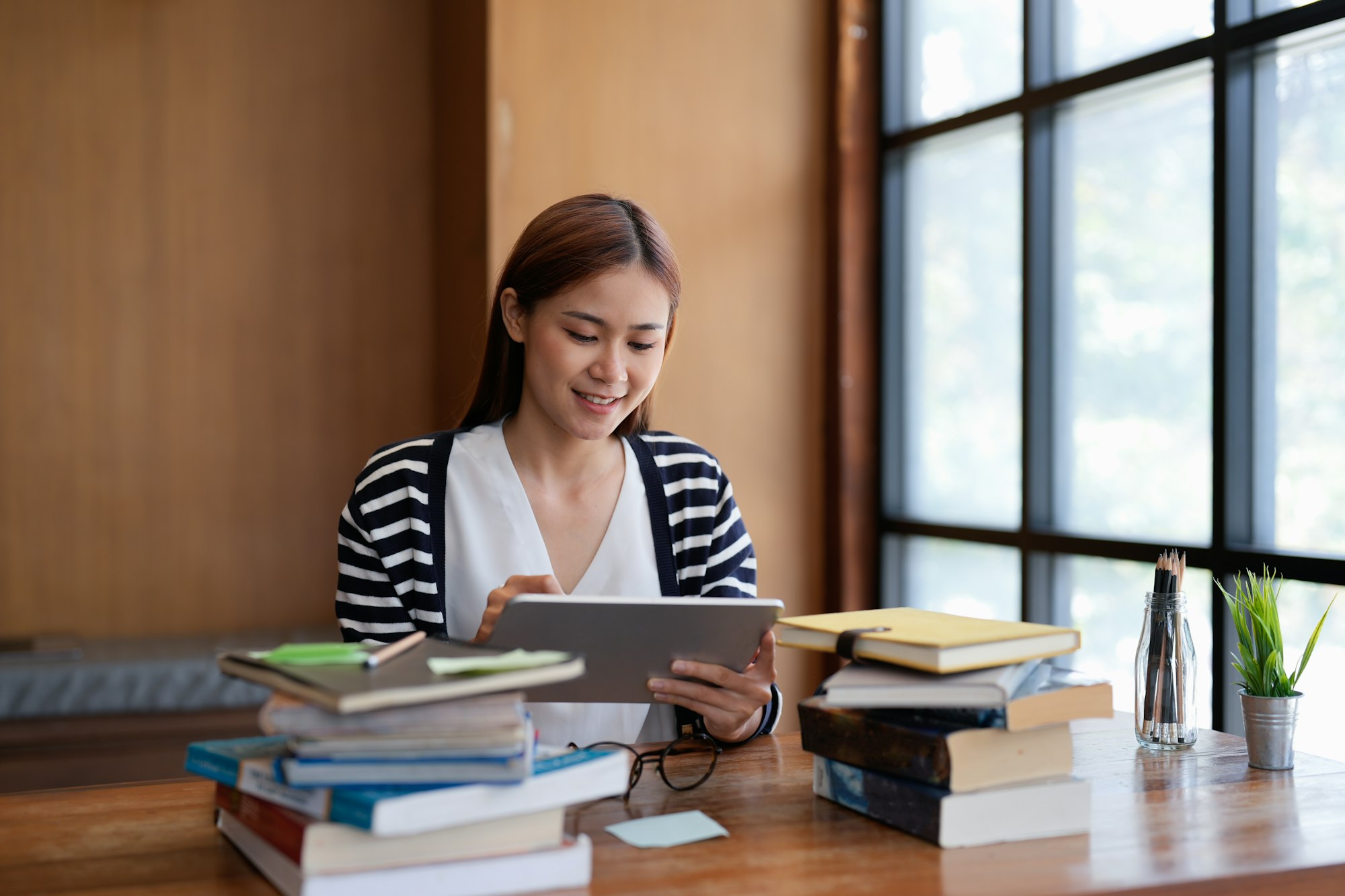 Young asian woman student working on digital tablet in library.