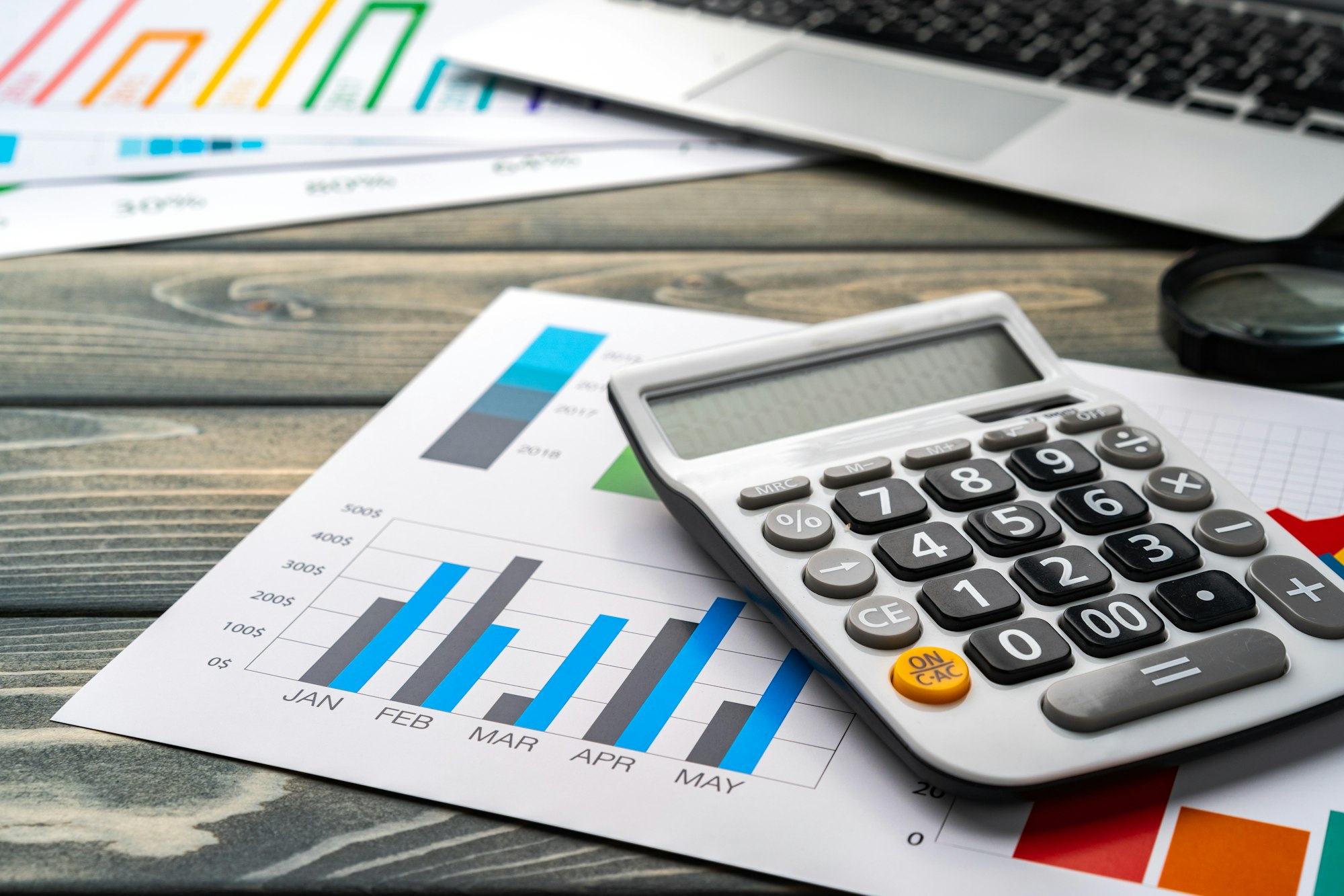 Business graphs paper and calculator on table